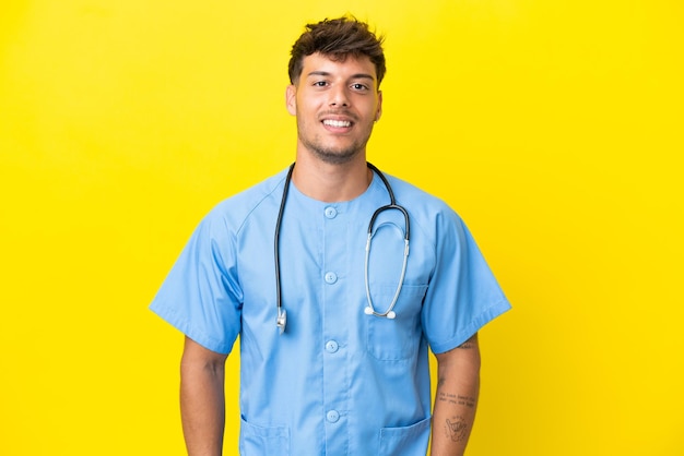 Joven cirujano médico hombre aislado sobre fondo amarillo riendo