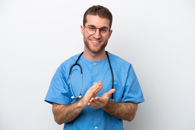 Joven cirujano médico hombre caucásico aislado de fondo blanco aplaudiendo después de la presentación en una conferencia