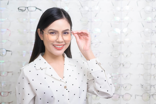 Joven clienta eligiendo anteojos en el centro óptico Concepto de cuidado de la vista
