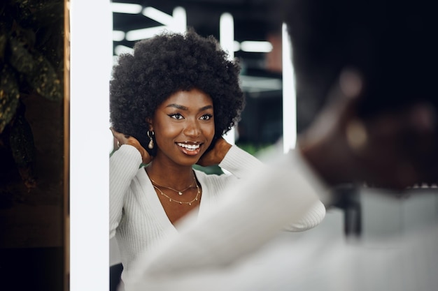 Una joven cliente africana que se peina en un salón de belleza