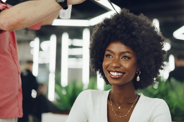 Una joven cliente africana que se peina en un salón de belleza