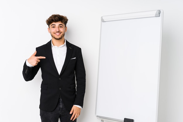 Joven coaching empresarial hombre árabe persona apuntando con la mano a una camisa copia espacio, orgulloso y confiado