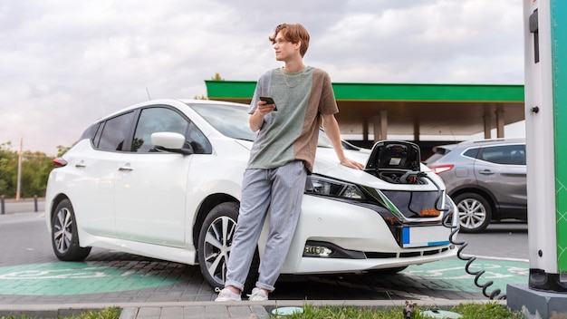 Joven con un coche eléctrico en la estación de carga en Chisinau Moldavia