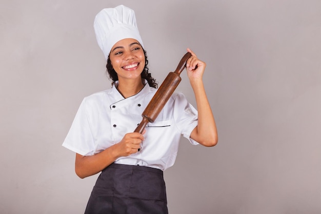 Joven cocinera brasileña negra sosteniendo un rodillo de madera para preparar pasta, pizza y pan