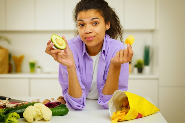 Joven cocinero en la cocina se confunde al comer aguacate o tacos