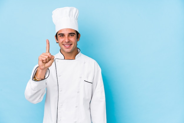 Joven cocinero hombre mostrando número uno con el dedo.