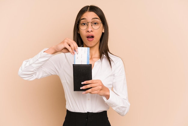 Joven colombiana sosteniendo un billete de avión aislado de fondo beige