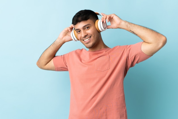 Joven colombiano aislado en azul escuchando música