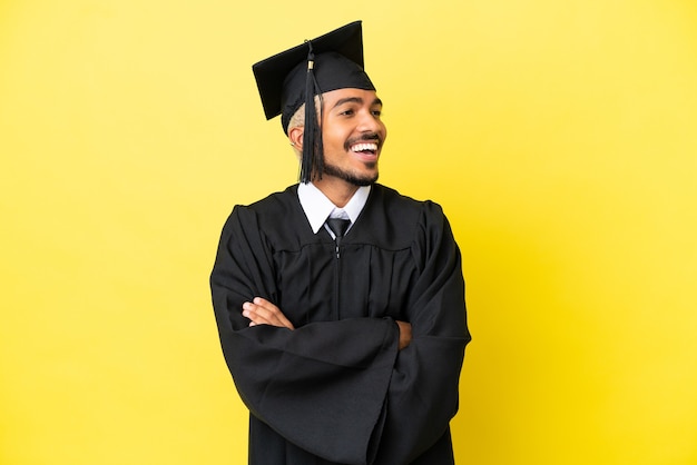 Joven colombiano graduado universitario aislado sobre fondo amarillo feliz y sonriente