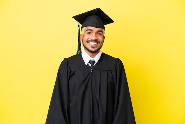 Joven colombiano graduado universitario aislado sobre fondo amarillo riendo