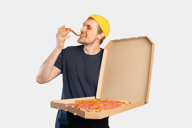 Joven comiendo pizza con una caja en sus manos