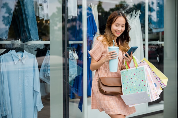 El joven comprador urbano disfruta de la comodidad moderna con las bolsas en la mano y el teléfono