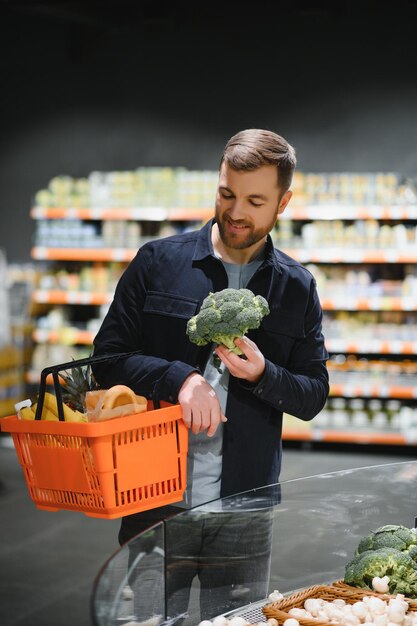Joven comprando comestibles en el supermercado Otros clientes en segundo plano Concepto de consumismo