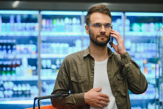 Joven comprando comestibles en el supermercado Otros clientes en segundo plano Concepto de consumismo