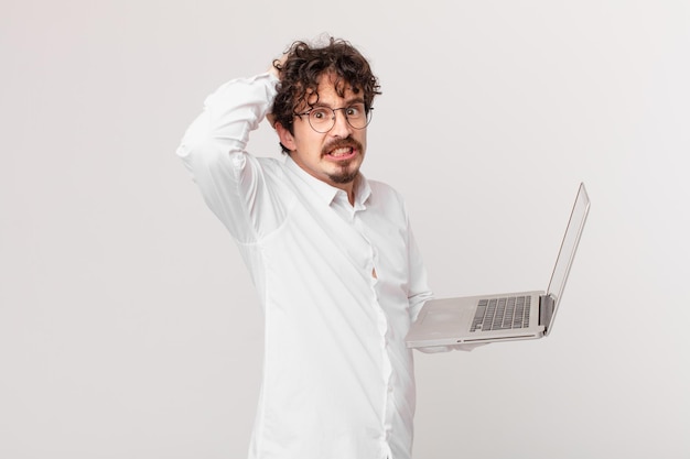 Foto joven con una computadora portátil que se siente estresado, ansioso o asustado con las manos en la cabeza