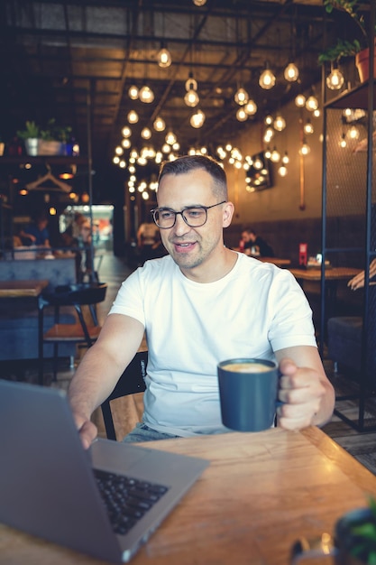 Un joven con una computadora portátil se sienta en un café.