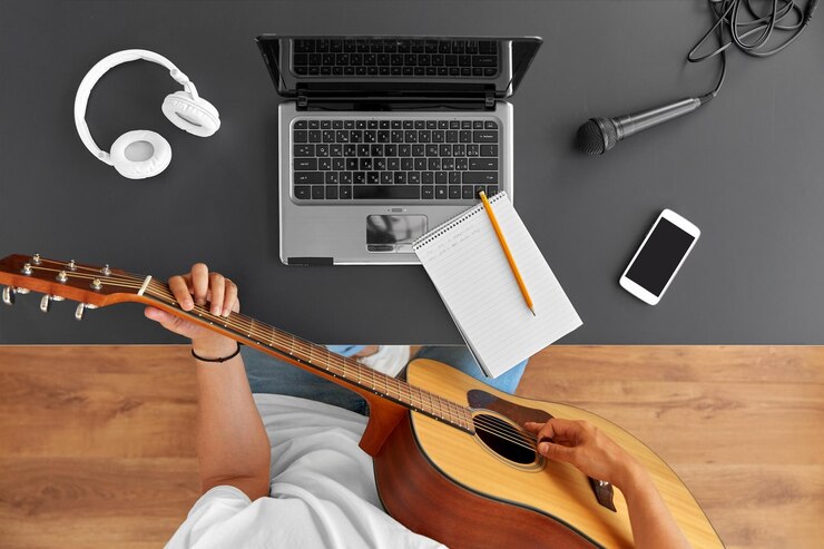 Foto un joven con una computadora portátil tocando la guitarra en la mesa