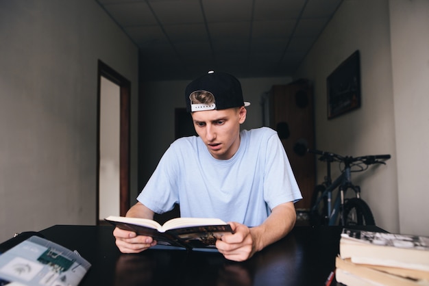 Joven concebido lee un libro interesante en casa en la habitación. Enseñando en casa.