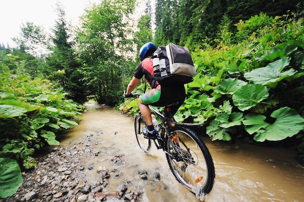 joven conduce bicicleta de montaña sobre el río de agua