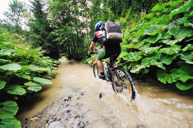 Un joven conduce una bicicleta de montaña sobre el río agua.