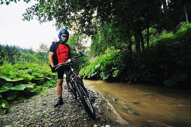 Un joven conduce una bicicleta de montaña sobre el río agua.