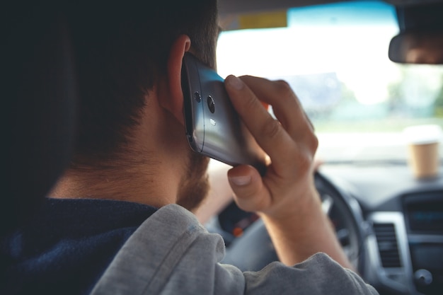 Joven conduciendo un coche hablando por teléfono móvil