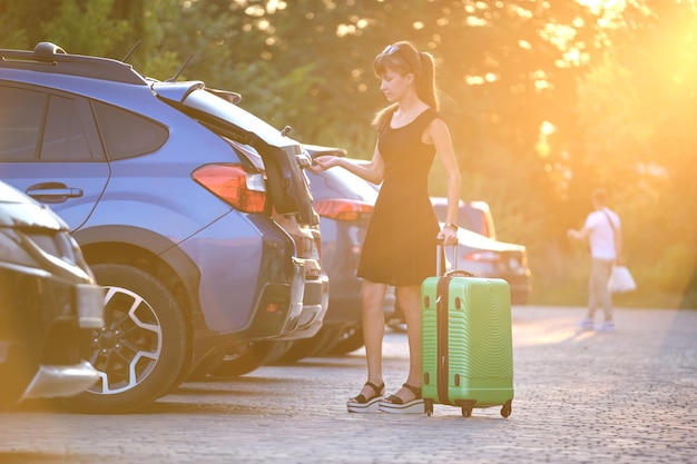 Joven conductora poniendo maleta de equipaje dentro de su automóvil Concepto de viaje y vacaciones