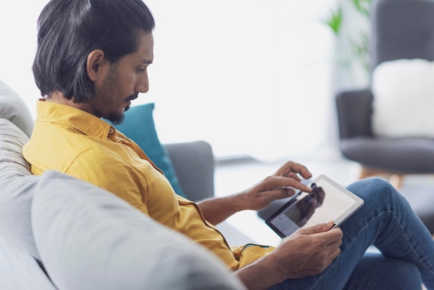 Joven conectándose con una tableta digital en casa