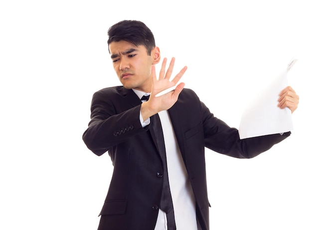 Joven confiado con cabello negro en camisa blanca y traje negro con corbata con papeles