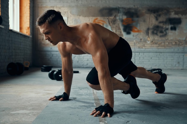 Foto joven confiado que parece concentrado mientras hace ejercicio en el gimnasio