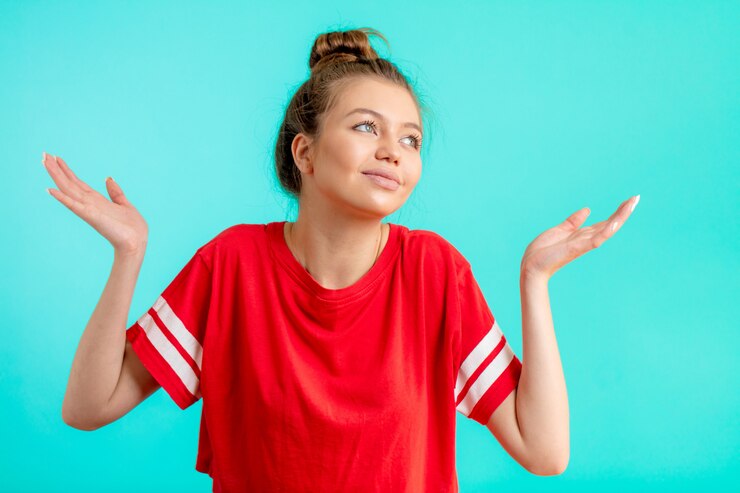 Foto joven confundida en moda camiseta roja con brazos encoge de hombros