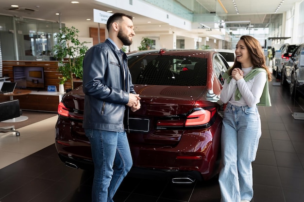 Una joven convence a su hombre en un concesionario de coches para que le compre un coche nuevo