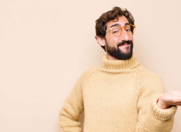 Joven cool sonriendo, sintiéndose confiado, exitoso y feliz, mostrando el concepto o idea en el espacio de copia en el lado contra la pared