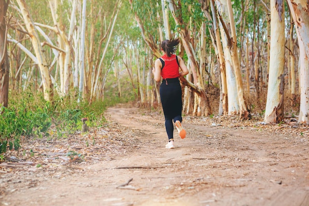 Joven corredor corriendo sendero en un bosque seco salvaje durante el verano en el camino forestal