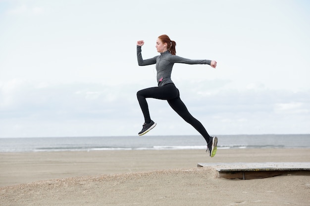 Joven corredor femenino saltando al aire libre