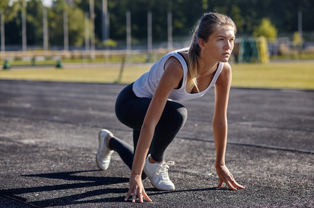 Una joven corredora preparándose para correr en la pista