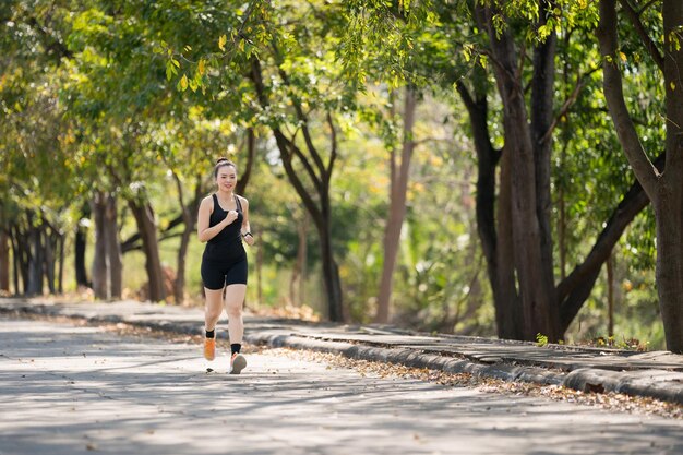 Una joven corredora con ropa de fitness corre en un parque de la ciudad rodeado de árboles y vegetación