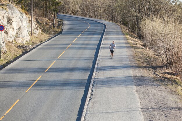 Joven corriendo afuera por una carretera de montaña vacía