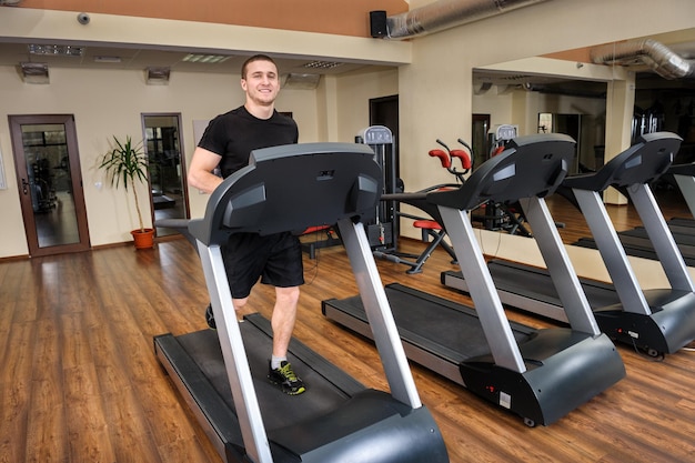 Joven corriendo en la caminadora en el gimnasio