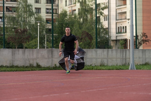 Joven corriendo con paracaídas en campo deportivo