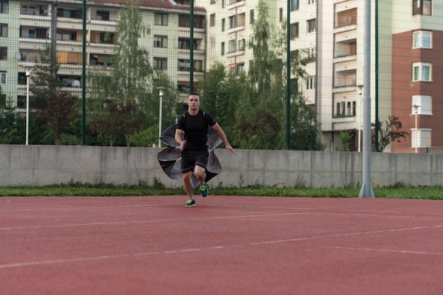 Joven corriendo con paracaídas en campo deportivo