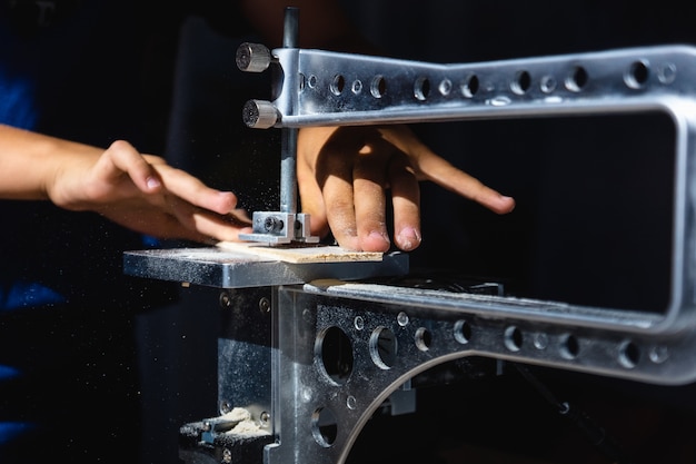 Un joven corta un patrón en madera contrachapada con una sierra eléctrica