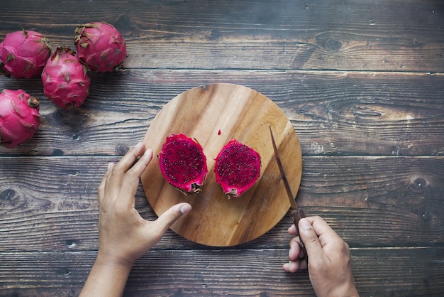 Joven cortando una fruta del dragón en una tabla de cortar