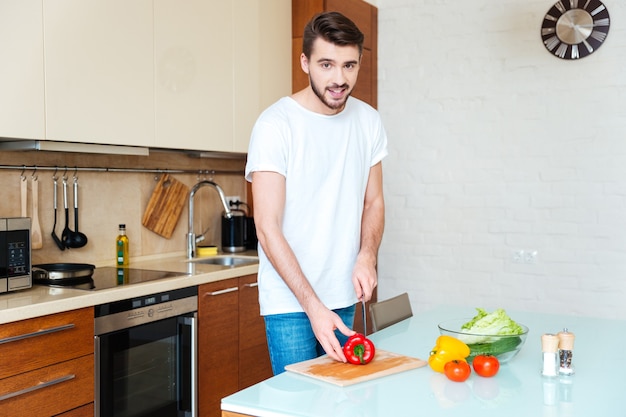 Joven cortando verduras en la cocina