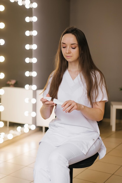 Joven cosmetóloga positiva sostiene un dispositivo para limpieza facial ultrasónica en sus manos