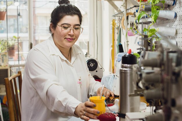 Foto joven costurera argentina mujer en el taller colocando el compañero en la mesa para continuar trabajando