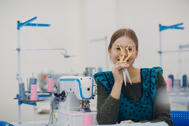 Joven costurera hermosa cose en la máquina de coser en fábrica