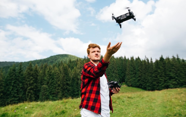 Joven creador de videos vuela un dron en las montañas lanza un dron de sus manos