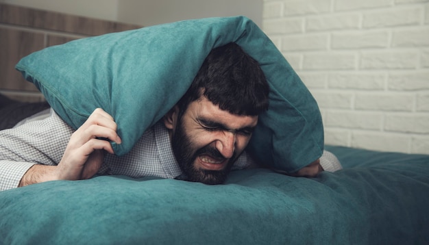 Joven cubre las orejas con una almohada