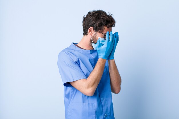 Joven cubriendo los ojos con las manos con una mirada triste y frustrada de desesperación, llorando, vista lateral. concepto de coronavirus